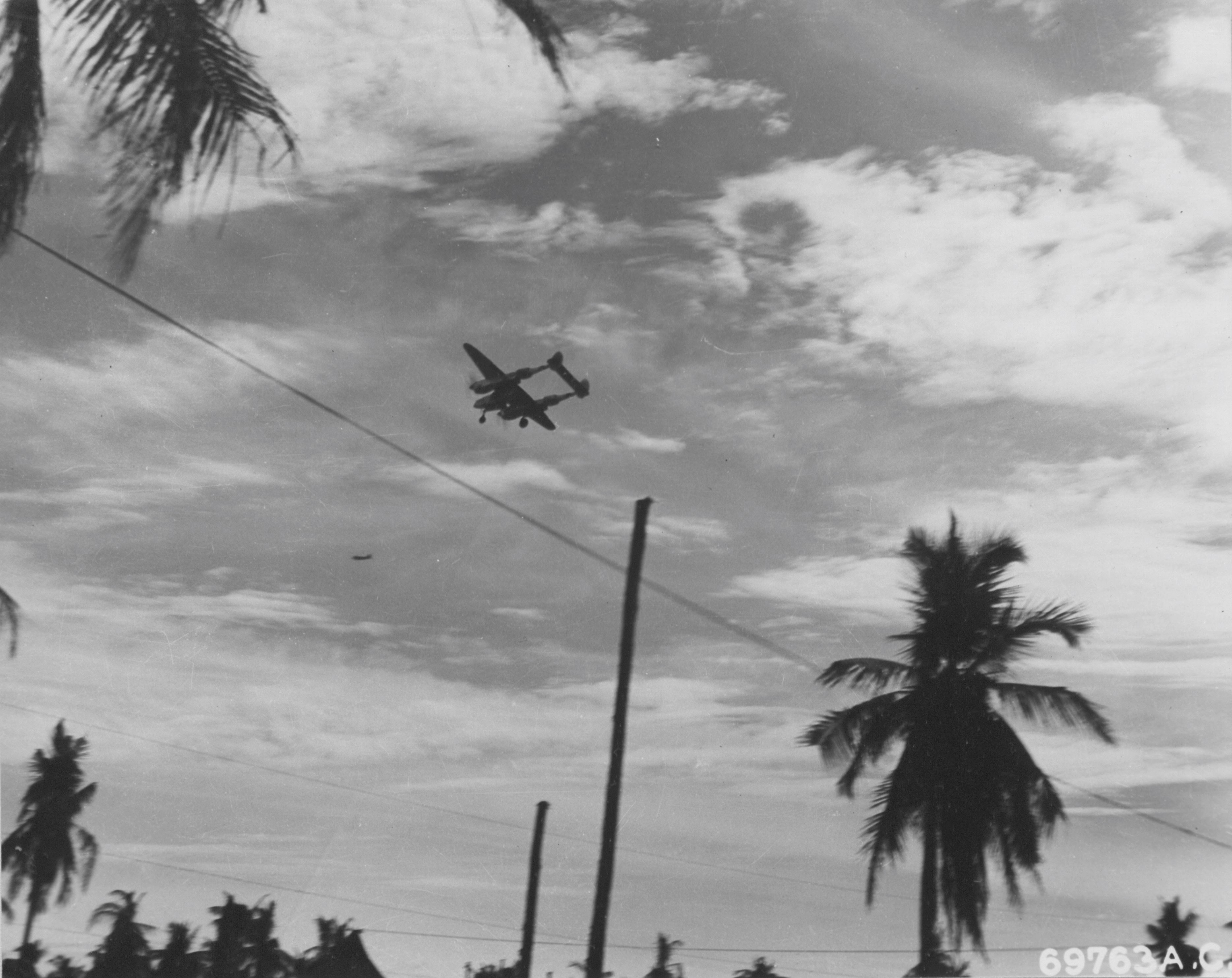 A Lockheed P-38 "Lightning" buzzing a base somewhere in the Philippine Islands.